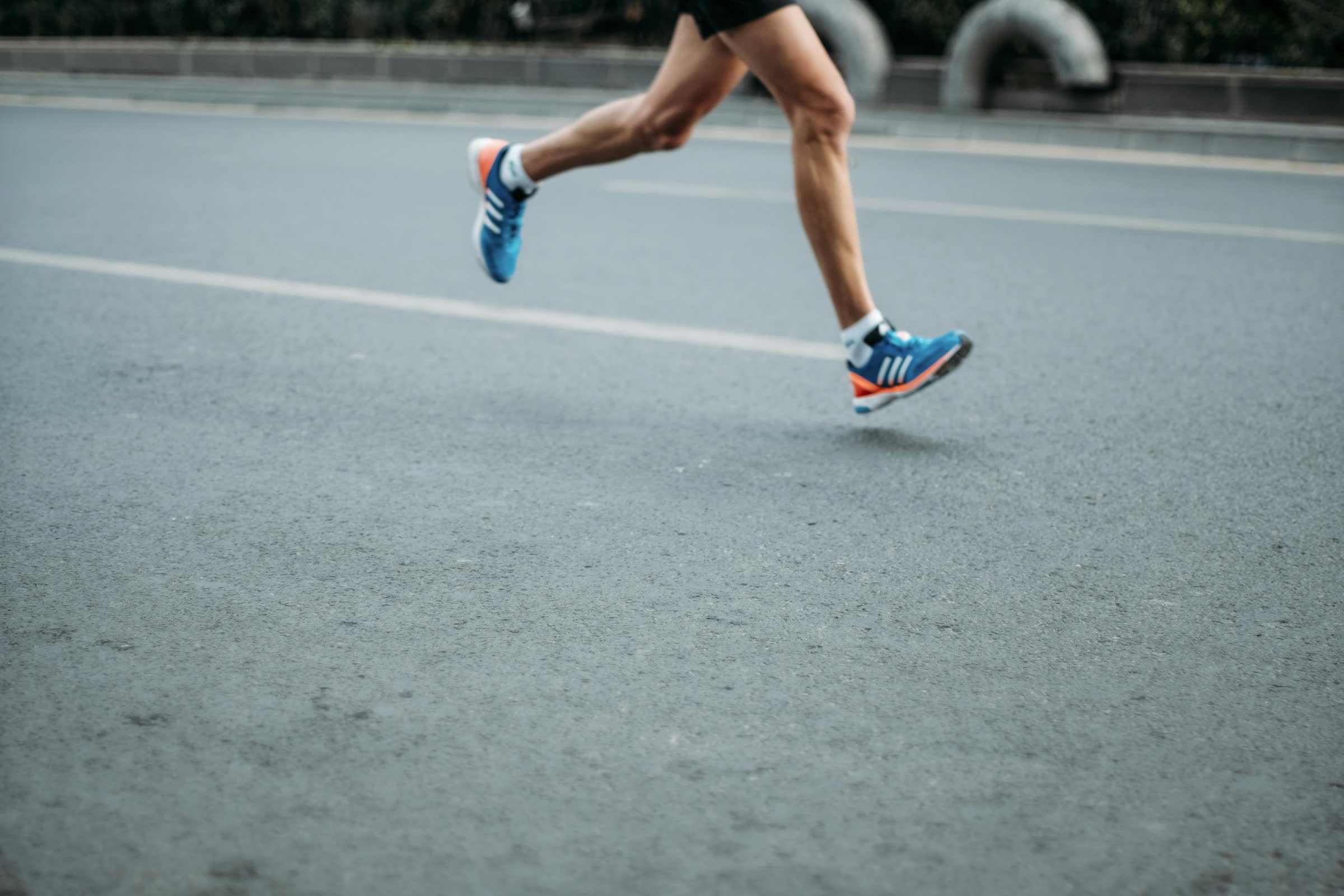 A runner mid-stride crossing an empty road